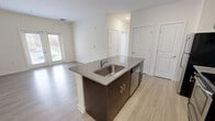 Located at 1351 Sapphire Dr in Virginia Beach, VA, this one-bedroom, one-bathroom residence offers a well-designed single-floor layout that maximizes functionality and comfort. The open-concept kitchen and living area serves as the heart of the home, anchored by a central island with granite countertops, an undermount stainless steel sink, and rich dark-brown cabinetry. Stainless steel appliances, including a refrigerator, range, and microwave, provide a modern, cohesive look. Light wood-style flooring flows throughout the main living area, complementing the neutral, cream-toned walls and recessed lighting overhead. The living room receives natural light through a set of glass French doors that open to an outdoor view, enhancing the airy feel of the space. The bedroom is generously sized, featuring plush carpet flooring, multiple windows with outdoor views, and a dedicated closet for storage. The bathroom includes tile flooring, a vanity with dark cabinetry, a window for natural light, and a full tub and shower combination. Clean lines, neutral finishes, and a practical layout define the overall ambiance of this well-appointed Virginia Beach residence.