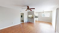 This single-story, 2-bedroom, 1-bathroom residence offers a practical and well-appointed layout designed for comfortable everyday living. The open-concept living room serves as the heart of the home, featuring warm hardwood-style flooring, neutral gray walls, a textured ceiling, and a ceiling fan with light fixture that promotes airflow and ambient lighting. Large windows allow natural light to filter throughout the space, enhancing its bright and airy feel.

The kitchen is efficiently designed in a galley style, showcasing white cabinetry, dark countertops, stainless steel appliances including a range and refrigerator, and a pass-through opening that connects to the living area. This layout promotes ease of movement and a sense of openness between the two spaces.

Both bedrooms are carpeted and finished in soft neutral tones, each equipped with a ceiling fan and window that invites natural light. The primary bedroom offers a generous footprint with closet access leading to the hallway. The second bedroom mirrors the same clean, comfortable aesthetic.

The bathroom is finished with wood-style flooring, a tiled shower-tub combination with curtain rod, and clean white fixtures. A hallway connects all rooms, providing a logical and efficient flow throughout the home.