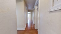 Located in Pittsburgh's charming Southside Slopes neighborhood, this 2-bedroom, 1-bathroom home offers a comfortable and well-laid-out single-floor living space. The home features two living areas connected by hallways, providing flexible use of space throughout.

The living rooms showcase warm hardwood flooring, large bay windows that invite abundant natural light, and classic cast-iron radiators that speak to the home's architectural heritage. One living area includes a wood-trimmed fireplace, adding a traditional focal point to the room.

Both bedrooms are carpeted and equipped with ceiling fans. They feature multiple windows offering neighborhood views, along with radiator heating and closet storage.

The kitchen is well-appointed with white cabinetry, a stainless steel dishwasher, a gas range, and a full-size refrigerator. Large windows brighten the tiled floor space, and the layout offers practical functionality for everyday cooking.

The bathroom features white tile walls with a classic burgundy accent border, a tub-shower combination, a vanity with under-sink storage, and a window for natural ventilation.

Throughout the home, detailed millwork including wide baseboards and framed doorways reflects the building's traditional character, making this a distinctive Pittsburgh residence.