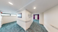 Located at 150 Huntington Ave in Boston's dynamic Back Bay/Fenway neighborhood, this single-floor community space offers a generously sized and thoughtfully designed environment built for comfort and social interaction. The layout spans a series of interconnected hallways and open areas, all unified by a contemporary teal-toned carpet that adds vibrancy underfoot throughout.

The main lounge area serves as the heart of the space, featuring a mix of seating options including tufted booth-style sofas, upholstered lounge chairs, and round dining tables with modern chairs — ideal for both casual gatherings and focused work. A dedicated snack and refreshment station is centrally positioned, complete with a coffee setup, vending machines, and a printer, making it a functional hub for daily use. Colorful wall art and bold typographic murals — featuring motivational phrases — bring energy and personality to the white walls.

Natural light filters in through a row of clerestory windows, brightening the lounge and lending an open, airy feel to the interior. A chalkboard column adds a creative, interactive touch to the space. The hallways are clean and well-lit, with recessed lighting and a bold purple accent wall providing a striking visual contrast. The bathroom is neatly finished with light wood-look tile flooring, a wall-mounted sink, mirror, and hand dryer. A dedicated laundry room completes the functional amenities of this well-appointed space.