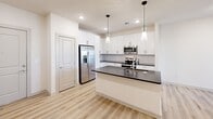 Located at 451 W Blount Ave in Knoxville, TN, this well-appointed 1-bedroom, 1-bathroom residence offers a thoughtfully designed single-floor layout with a bright, modern aesthetic throughout. The open-concept kitchen and living area serves as the heart of the home, featuring light hardwood-style flooring, recessed lighting, and a striking kitchen island with a dark countertop and integrated sink. The kitchen is outfitted with crisp white shaker cabinets, a matching dark countertop, a subway tile backsplash, and a full suite of stainless steel appliances, including a side-by-side refrigerator with ice maker, electric range, and over-the-range microwave. Pendant lighting above the island adds a stylish finishing touch. Natural light fills the living area through a glass door that opens to a private balcony. The bedroom is a comfortable, carpeted retreat with dual windows, a ceiling fan, and direct access to the bathroom. The bathroom is elegantly finished with light wood-look tile flooring, a floating white vanity with a dark countertop, a large mirror, and a full soaking tub. Additional conveniences include two closets, a dedicated laundry area, a utility room, and a hallway connecting the living spaces seamlessly.
