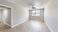 This single-floor apartment offers five bedrooms and two full bathrooms within a thoughtfully arranged layout. The neutral gray walls and white trim create a clean, cohesive aesthetic throughout. Bedrooms feature soft carpeting and are filled with natural light through blinded windows, with ceiling fans included in select rooms for added comfort. The generously sized primary bedroom stands out with dual windows and laminate wood flooring, enhancing its bright and airy feel. Closet space is well-distributed, with multiple bedrooms equipped with wide hanging rods for organized storage. The kitchen is efficiently designed with white cabinetry, light countertops, stainless steel appliances including a refrigerator and range, and light wood-look tile flooring that extends the clean aesthetic. Two full bathrooms are present — one features classic white subway tile surrounding a tub-shower combo with a window, while the second offers a bright white tub-shower unit with light wood-look flooring, a toilet, and a vanity. Textured ceilings are found throughout, adding a subtle architectural detail. The overall ambiance is fresh, functional, and move-in ready, with consistent finishes tying each room together seamlessly.