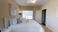 This single-floor residence offers a thoughtfully designed layout that balances comfort and functionality throughout. The living room is a welcoming space finished with warm wood-look flooring, crown molding, and a sliding glass door that fills the room with natural light and provides access to an outdoor patio. Adjacent to the living area, the dining space features track lighting overhead and a built-in desk nook, making it as practical as it is inviting.

The galley-style kitchen is efficiently arranged with white cabinetry, ample counter space, and a full suite of appliances including a refrigerator, electric range, and dishwasher. Wood-look flooring continues throughout, adding warmth and cohesion.

The primary bedroom is generously sized with plush carpet, a ceiling fan, a window offering outdoor views, and direct access to a closet. A second bedroom mirrors the comfortable feel, featuring carpet, a ceiling fan, flanking nightstands, and warm ambient lighting. Both bedrooms share access to a full bathroom appointed with a vanity, wide mirror, and a shower-tub combination.

A dedicated laundry area with washer and dryer hookups, wire shelving for storage, and a water heater rounds out the unit's practical amenities, making this a complete and move-in ready space.