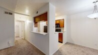 Located at 2626 Thousand Oaks Dr in San Antonio, TX, this 2-bedroom, 1-bathroom single-floor unit offers a well-organized and functional layout. The living room is a standout space, featuring vaulted ceilings that lend an open, airy feel, soft carpeting underfoot, and a classic brick fireplace framed by a white mantel — creating a warm and inviting focal point. Vertical blinds cover a large sliding door, allowing natural light to filter through. The adjacent dining area features warm hardwood-style flooring and a pendant light fixture, with a window offering a view of the greenery outside. The galley-style kitchen is efficiently designed with rich wood cabinetry, light countertops, a double sink, and black appliances including a refrigerator, range, and built-in microwave. A hallway connects the living areas to the two carpeted bedrooms, each offering natural light through windowed blinds and a comfortable, quiet atmosphere. The bathroom is clean and practical, featuring wood vanity cabinetry, a light countertop, and a shower/tub combination. A dedicated closet and hallway complete the layout, making this a well-appointed and efficient home.