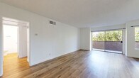 Located at 19050 Sherman Way in Los Angeles, CA, this well-appointed 1-bedroom, 1-bathroom unit offers a thoughtfully designed single-floor layout with modern finishes throughout. Warm wood-look flooring runs continuously across all rooms, creating a cohesive and inviting atmosphere. The spacious living room is bathed in natural light, courtesy of large sliding glass doors that open directly onto a private balcony with lush tree views — a standout feature of the space. A ceiling fan adds comfort to the living area, which also accommodates a dining space adjacent to the kitchen. The galley-style kitchen is outfitted with white cabinetry, white countertops, a range, and a skylight overhead that floods the space with additional natural light. The generously sized bedroom features mirrored sliding closet doors that enhance the sense of space, along with a large window framing greenery views. Five closets throughout the unit provide exceptional storage. The clean, white bathroom includes a vanity with white cabinetry and a bathtub. A hallway connects the rooms efficiently. With a neutral color palette, textured ceilings, and an abundance of natural light, this unit offers a bright, clean, and functional living environment in the Reseda neighborhood of Los Angeles.