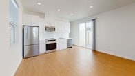 Located at 15912 Chase Rd in Fontana, CA, this well-designed one-bedroom, one-bathroom unit offers a thoughtfully organized single-floor layout. The open-concept living and kitchen area serves as the heart of the space, featuring light bamboo-style hardwood flooring that runs throughout the entire unit. The kitchen is outfitted with crisp white shaker cabinetry, a full suite of stainless steel appliances including a refrigerator, electric range, built-in microwave, and dishwasher, as well as a single-basin sink. Recessed lighting illuminates the space, while a sliding glass door with sheer curtains opens to a private outdoor area, bringing in abundant natural light. The bedroom offers a comfortable footprint with two windows fitted with white blinds, allowing for excellent natural light and ventilation. A dedicated closet with a rod and shelf provides practical storage. The bathroom features a white vanity with an undermount sink, a large mirror, and a shower-tub combination enclosed by a glass sliding door. Consistent light wood flooring and a clean white palette carry through the bathroom, tying the unit together with a cohesive, modern aesthetic throughout.