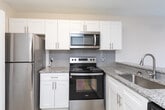Located at 4260 Brownsboro Rd in Winston-Salem, NC, this single-floor residence offers a well-organized layout with a variety of functional spaces throughout. The kitchen is outfitted with white shaker-style cabinetry, granite countertops, a subway tile backsplash, stainless steel appliances including a refrigerator and microwave, and light wood-style luxury vinyl flooring that extends throughout the main living areas. A conveniently tucked stacked washer and dryer unit is accessible via a dedicated closet just off the kitchen, providing in-unit laundry without sacrificing space. The dining area sits adjacent to the kitchen and features a chandelier pendant light and a large sliding glass door dressed with vertical blinds, allowing ample natural light to filter in. The living room offers a bright, open feel with light flooring and a front entry door. Bedrooms are finished with neutral carpet and textured ceilings, each with windows that bring in natural light. One bedroom includes access to a spacious walk-in closet equipped with wire shelving for organized storage. The bathroom features a full tub-shower combination with a clean white surround. Throughout, the space maintains a neutral, light color palette that creates a calm and versatile ambiance.