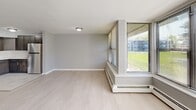 Located at 1 Woodbine Ave, Unit 7D in Avenel, NJ, this one-bedroom, one-bathroom residence offers a thoughtfully utilized single-floor layout. Light wood-style flooring flows consistently throughout the living areas and bedroom, lending a clean, cohesive aesthetic to the space. The combined kitchen and living room forms the heart of the unit, where the kitchen is equipped with rich dark wood cabinetry, marble-style countertops, a stainless steel refrigerator, and a undermount sink — all opening directly into the bright, open living area. Large windows fitted with horizontal blinds line the living room, allowing generous natural light to fill the space and offering views of the surrounding greenery. The spacious primary bedroom continues the light flooring and neutral gray tones, featuring multiple windows that further enhance its airy feel, along with closet access and baseboard heating. The full bathroom is finished with large-format beige subway tile surrounding a soaking tub and shower combination, brushed nickel fixtures, and a white vanity with an undermount sink. Throughout the residence, a soft gray and white color palette, clean white trim, and consistent flooring choices create a calm, move-in-ready environment.