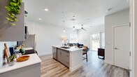 Located at 2830 Northtowne Ln in Reno, NV, this thoughtfully designed unit offers 3 bedrooms and 3 bathrooms across a single-level, open-concept floor plan. The kitchen is a standout feature, showcasing gray cabinetry, white quartz countertops, a center island with pendant lighting, subway tile backsplash, and stainless steel appliances — including a refrigerator, range, and microwave. The kitchen flows seamlessly into the living room, which is brightened by large windows with blinds, a ceiling fan, and a sliding glass door that opens to an outdoor patio with views of surrounding greenery. Luxury vinyl plank flooring runs throughout, adding warmth and cohesion to the space. The bedrooms are well-proportioned and bathed in natural light through generously sized windows. The primary bedroom includes a walk-in closet with built-in wire shelving. Each of the three bathrooms features a gray vanity with white countertops, a backlit mirror, and clean, modern finishes with white tile. A hallway connects all rooms efficiently, completing a practical and polished layout. The overall aesthetic is modern and bright, with a neutral palette that creates a clean, inviting atmosphere throughout.