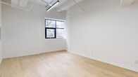 Located at 36 N Narberth Avenue in Narberth, PA, this thoughtfully designed one-bedroom, two-bathroom unit offers a compelling blend of industrial character and modern refinement. Light-toned hardwood flooring runs throughout, complementing the unit's notably elevated ceilings, which lend an open, airy quality to every room. Exposed ductwork and structural elements add an industrial edge, while clean white walls and abundant natural light from black-framed windows maintain a bright, contemporary feel.

The kitchen serves as a centerpiece of the unit, featuring a dramatic floor-to-ceiling marble-clad island with an integrated sink and brushed gold faucet. White shaker cabinetry with gold hardware lines the walls above dark marble countertops, and stainless steel appliances complete the refined aesthetic. Pendant lighting with matte black and gold fixtures adds a stylish focal point above the island.

The bedroom offers a comfortable footprint with a double sliding-door closet and a black-framed window with outdoor views. Two well-appointed bathrooms feature marble-look tile throughout; one includes a glass-enclosed walk-in shower with a rain showerhead, while the second offers a tub-shower combination. An additional flexible room provides versatile space for various uses.