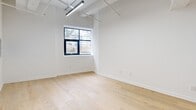 Located at 36 N Narberth Avenue in Narberth, PA, this thoughtfully designed one-bedroom, two-bathroom unit offers a compelling blend of industrial character and modern refinement. Light-toned hardwood flooring runs throughout, complementing the unit's notably elevated ceilings, which lend an open, airy quality to every room. Exposed ductwork and structural elements add an industrial edge, while clean white walls and abundant natural light from black-framed windows maintain a bright, contemporary feel.

The kitchen serves as a centerpiece of the unit, featuring a dramatic floor-to-ceiling marble-clad island with an integrated sink and brushed gold faucet. White shaker cabinetry with gold hardware lines the walls above dark marble countertops, and stainless steel appliances complete the refined aesthetic. Pendant lighting with matte black and gold fixtures adds a stylish focal point above the island.

The bedroom offers a comfortable footprint with a double sliding-door closet and a black-framed window with outdoor views. Two well-appointed bathrooms feature marble-look tile throughout; one includes a glass-enclosed walk-in shower with a rain showerhead, while the second offers a tub-shower combination. An additional flexible room provides versatile space for various uses.
