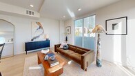 Located in the heart of Los Angeles, this thoughtfully designed 2-bedroom, 2-bathroom residence offers a single-floor open-concept layout filled with natural light. Light hardwood flooring flows throughout, complementing the crisp white walls and recessed lighting that give the space a clean, modern aesthetic.

The kitchen is a standout feature, showcasing a sleek combination of white cabinetry and warm wood upper cabinets, a large central island with a quartz countertop, and a full suite of stainless steel appliances including a gas range, built-in microwave, and refrigerator. A pantry and dedicated laundry area add practical convenience.

The open living and dining area is anchored by floor-to-ceiling sliding glass doors that lead to a private balcony, offering city views and abundant natural light. The spacious primary bedroom continues this indoor-outdoor connection with its own balcony access and generous closet space. The second bedroom is bright and versatile, ideal as a guest room or home office.

Both bathrooms are finished with striking floor-to-ceiling marble-style tile, glass-enclosed tub-shower combinations, wall-mounted fixtures, and wood-accented vanities, delivering a spa-like atmosphere. A connecting hallway ties all rooms together efficiently, completing this well-appointed urban residence.