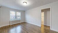 This 2-bedroom, 1-bathroom residence at 510 Milburn Ave in Springfield, NJ offers a thoughtfully designed single-floor layout that makes efficient use of its space. Rich, dark hardwood flooring flows consistently throughout the hallway, living room, and both bedrooms, lending warmth and cohesion to the interior. A welcoming hallway with textured white walls and ceiling lighting connects the main areas of the home. The living room is bright and open, featuring crown molding and natural light from a large window with outdoor views. Both bedrooms are comfortably sized, each featuring hardwood floors, windows with natural light, a radiator unit, and dedicated closets with built-in clothing rods for ample storage. The primary bedroom is notably spacious and leads conveniently to an adjacent room. The kitchen is clean and modern, equipped with stainless steel appliances including a gas range, over-the-range microwave, and refrigerator, complemented by white shaker cabinetry, a tiled backsplash, neutral countertops, and light tile flooring. The bathroom is elegantly finished with white subway tile, a decorative mosaic accent border, a tub-shower combination with glass sliding doors, a white vanity, and a mirrored medicine cabinet — all accented with brushed nickel hardware.