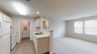Located at 815 Cole Dr in Johnstown, Ohio, this single-floor residence offers a practical and comfortable layout designed for everyday living. The open-concept living and dining area features a combination of hardwood-style flooring and plush carpeting, with neutral gray walls and a textured ceiling throughout that lend a clean, cohesive feel. A pendant light fixture adds a warm accent to the dining space.

The kitchen is efficiently designed with light maple cabinetry, white countertops, a double-basin sink, and white appliances including a refrigerator and electric range. A skylight and recessed lighting brighten the space, while a pass-through peninsula connects the kitchen to the main living area. Adjacent to the kitchen is a dedicated laundry room with a full-size washer and dryer and overhead wire shelving for added storage.

The bedrooms are carpeted and generously sized, with large windows that invite natural light and offer views of the surrounding neighborhood. At least one bedroom includes a walk-in closet with built-in shelving. The bathrooms feature hardwood-style flooring, a white vanity with lighted mirror, and one includes a full tub/shower combination. The overall ambiance is bright, clean, and move-in ready.
