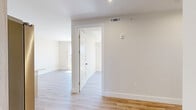 Located at 39 Lexington Ave in Passaic, NJ, this thoughtfully designed 2-bedroom, 2-bathroom unit offers a clean, modern aesthetic throughout its single-floor layout. Light wood-tone luxury vinyl flooring flows seamlessly across every room, complemented by crisp white walls and recessed lighting that create a bright, welcoming ambiance.

The open-concept kitchen and living area serves as the heart of the home, showcasing light wood grain cabinetry extending to the ceiling, a white subway tile backsplash, and a central island with a quartz-style countertop. Stainless steel appliances — including a French door refrigerator, gas range, and built-in microwave — complete the contemporary kitchen.

Both bedrooms are well-proportioned, with the primary bedroom offering generous space. Large windows in the bedrooms invite abundant natural light and provide open views of the surrounding Passaic neighborhood. The rooms feature clean lines, neutral tones, and recessed lighting.

The two bathrooms are finished with modern fixtures, including a floating wood-toned vanity with an LED-backlit mirror in one, and a sleek glass-enclosed tub-shower combination in the other — both finished with the same warm wood flooring for a cohesive look throughout the unit.