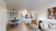 This thoughtfully designed 2-bedroom, 1-bathroom residence offers a cohesive, open-concept layout that maximizes functionality and flow throughout its single floor. The kitchen serves as a central hub, featuring white shaker cabinetry, gray quartz countertops, a subway tile backsplash, stainless steel appliances including a refrigerator, range, and microwave, and a peninsula island with a deep undermount sink. A built-in pantry provides additional storage. Light wood-style flooring runs throughout, lending warmth and continuity across all areas. The open living and dining area benefits from large windows and a glass door that invite abundant natural light and views of lush greenery, creating a bright, airy ambiance. The living room offers a comfortable retreat with access to the outdoors. The primary bedroom features multiple windows framing tree-lined views, providing a serene and naturally lit environment. The second bedroom is equally well-appointed with clean white walls and hardwood-style flooring. The full bathroom includes white cabinetry, a gray countertop vanity with a large mirror, a tub-shower combination, and wood-look flooring. A dedicated closet completes the layout, offering practical storage within this efficiently designed residence.