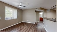 This thoughtfully designed two-bedroom, two-bathroom residence in Los Angeles, CA offers a functional and comfortable single-floor layout. The living area features rich dark hardwood-style flooring, neutral taupe walls, and a ceiling fan, creating a warm and inviting atmosphere. Large windows dressed with vertical blinds allow natural light to filter throughout, with views of surrounding greenery visible from multiple rooms.

The kitchen is equipped with warm wood cabinetry, dark countertops, and black appliances including a range, microwave, and refrigerator. A breakfast bar peninsula separates the kitchen from the living area, adding both visual interest and practical utility. Track lighting and a flush-mount ceiling fixture provide ample illumination.

Both bedrooms are generously sized and feature plush wall-to-wall carpeting, ceiling fans, and windows overlooking outdoor greenery, offering a quiet retreat. The primary bedroom includes direct access to an en-suite bathroom.

Both bathrooms are appointed with warm wood vanity cabinetry, light countertops, large mirrors with overhead lighting, and wood-style flooring. One bathroom includes additional overhead storage cabinetry. The overall aesthetic is clean, cohesive, and move-in ready, with a consistent neutral palette carried throughout the home.