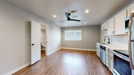This single-floor space presents a thoughtfully updated interior with a cohesive, contemporary design throughout. Wood-look plank flooring runs continuously across all areas, creating a unified aesthetic while adding warmth to the neutral gray-toned walls and bright white trim.

The kitchen is well-equipped with stainless steel appliances, including a refrigerator, gas range, microwave, and dishwasher. White shaker-style cabinetry with a subway tile backsplash adds a clean, modern look, while recessed lighting ensures the space is well-lit. A ceiling fan is centrally positioned overhead, contributing to air circulation across the open living area.

In-unit laundry is conveniently stacked near the main entry, alongside an electrical panel discreetly mounted on the wall. The front entry door features a modern hardware finish, and the open layout allows the kitchen and living areas to flow naturally together.

The bedroom is a comfortable, well-proportioned space with a window fitted with blinds, recessed lighting, a ceiling fan, and direct access to a full bathroom. Natural light filters in through multiple windows, keeping the interior feeling open and bright. Overall, the space offers a practical, modern living environment with quality finishes throughout.