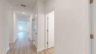 Located at 129 Mainland Lakes Dr in Bluffton, SC, this single-story, three-bedroom, two-bathroom home offers a clean, modern aesthetic throughout. Light-toned luxury vinyl plank flooring flows seamlessly across all rooms, complementing the bright white walls and crisp trim work that define the interior. The open-concept kitchen and living area serves as the heart of the home, showcasing white shaker cabinetry, granite countertops with a subway tile backsplash, stainless steel appliances including a refrigerator, range, and microwave, and a peninsula with a sink — ideal for both cooking and casual dining. The generous living area features recessed lighting and a ceiling fan, creating a comfortable, airy atmosphere. The primary bedroom is a well-proportioned retreat, complete with a ceiling fan, natural light from a window with outdoor views, and direct access to its en-suite bathroom. The primary bath impresses with a dual-sink vanity, white cabinetry, bright countertops, and a glass-enclosed shower. Two additional bedrooms offer ample space, each with ceiling fans and easy hallway access. A dedicated laundry room houses a full-size washer and dryer with built-in wire shelving above. A walk-in closet provides generous storage with wire rack shelving on multiple walls, rounding out this well-appointed home.
