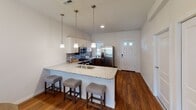 This single-floor residence offers a thoughtfully designed layout that balances comfort and functionality throughout. The open-concept living area is anchored by rich hardwood flooring and flows seamlessly into a dining space and a well-equipped kitchen. The kitchen stands out with two-tone cabinetry — crisp white upper cabinets paired with dark lower cabinets — granite countertops, a tile backsplash, stainless steel appliances, and a peninsula with bar seating illuminated by pendant lighting. The living room features French doors that invite natural light and provide outdoor access, creating an airy, welcoming atmosphere.

The primary bedroom is a comfortable retreat, carpeted and bathed in natural light from multiple windows, with direct access to a spacious walk-in closet. Additional bedrooms are carpeted and bright, offering versatile use as sleeping quarters or flex spaces. The bathrooms are finished with dark wood vanities, ample storage, and shower-tub combinations. A dedicated in-unit laundry room with a full-size washer and dryer adds everyday convenience. Throughout the home, neutral tones, consistent finishes, and thoughtful design details create a cohesive and inviting living environment.