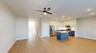 Located at 412 Ophelia Way in Greenville, NC, this well-designed two-story home offers two bedrooms, three bathrooms, and a thoughtfully organized layout spread across two floors. The main level serves as the heart of the home, featuring a seamless open-concept living, dining, and kitchen area finished with light wood-tone flooring and recessed lighting throughout. The kitchen stands out with its two-tone cabinetry — crisp white upper cabinets paired with bold navy lower cabinets — a light quartz countertop island, stainless steel appliances, and a classic subway tile backsplash. A ceiling fan anchors the living area, while a large window and glass-panel door fill the dining space with natural light. The attached garage is clean and well-lit, equipped with an automatic opener. A staircase with warm wood treads and white risers connects the floors, accented by a wood handrail. Upstairs, the generously sized primary bedroom features a ceiling fan, hardwood-style flooring, and access to multiple walk-in closets with built-in wire shelving. The primary bathroom includes a soaking tub with tiled surround. Additional highlights include a dedicated laundry room, a pantry, and ample closet storage across five closets throughout the home.