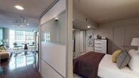 This contemporary single-floor residence showcases a thoughtfully designed open layout with a strong sense of urban sophistication. The highly polished concrete floors run throughout the main living areas, reflecting natural light that pours in through expansive floor-to-ceiling windows, framing impressive city skyline views. Exposed industrial-style ductwork adds a loft-inspired character to the living space, which is anchored by a teal accent wall and a cozy seating area with generous window coverage on two sides.

The kitchen is outfitted with sleek white cabinetry extending to the ceiling, dark granite countertops, a blue-grey subway tile backsplash, and a full suite of stainless steel appliances including a dishwasher, range, built-in microwave, and refrigerator. Track lighting overhead enhances both functionality and ambiance.

The bedroom features a striking black-and-white chevron accent wall, a built-in open closet, and a large floor mirror that amplifies the sense of space. Frosted glass sliding panels elegantly separate the sleeping area from the main corridor. The bathroom carries the teal color palette with bold wall paint, a floating dark-wood vanity, and tile flooring, maintaining a cohesive modern aesthetic throughout the residence.