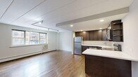 Located in Chicago's Edgewater neighborhood, this one-bedroom, one-bathroom unit at 6119 N Kenmore Ave offers a well-designed layout with a thoughtful blend of modern updates and classic character. Rich hardwood floors flow throughout the entire space, anchoring each room with warmth and continuity.

The open-concept living and kitchen area serves as the heart of the unit. The kitchen is outfitted with dark espresso cabinetry, a crisp white subway tile backsplash, a white quartz countertop, and a full suite of stainless steel appliances including a refrigerator, dishwasher, microwave, and range. A peninsula provides additional counter space and creates a natural divide between the kitchen and the open living area. Track lighting overhead and recessed fixtures illuminate the space, while a large window draws in natural light and neighborhood views.

The bedroom is a comfortable, well-proportioned room featuring a window with street views, baseboard heating, and a wall-unit AC. A pair of mirrored sliding closet doors add both storage and a sense of depth to the room.

The bathroom is notably stylish, featuring floor-to-ceiling textured mosaic tile surrounding the soaking tub and shower combination, complemented by a modern floating vanity with clean white cabinetry and a chrome faucet.