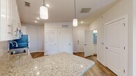 Located at 700 City View Loop in Midlothian, VA, this single-floor residence offers a thoughtfully designed layout with one bedroom, one bathroom, and a dedicated closet. The open kitchen serves as a central highlight, showcasing crisp white shaker cabinetry extending to the ceiling, light grey subway tile backsplash, and granite countertops with a peninsula island. Stainless steel appliances — including a range, microwave, dishwasher, and refrigerator — complement the space, while stylish pendant lighting and recessed fixtures provide both task and ambient illumination. Durable wood-look flooring runs throughout the main living and kitchen areas, lending warmth and continuity. The bedroom is carpeted for comfort, benefits from natural light through a window with blinds, and features a ceiling fan. It connects directly to a dedicated closet and the full bathroom. The bathroom is finished with a white shaker vanity topped with granite, a tiled shower-tub combination, and wood-look flooring that echoes the main living area. A louvered closet door near the kitchen entry adds a classic detail. Clean white walls and neutral tones throughout create a bright, move-in-ready atmosphere suited for comfortable everyday living.