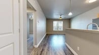 Located at 517 S Locust St in Denton, TX, this single-story, 4-bedroom, 2-bathroom home offers a practical and well-appointed layout. The open-concept kitchen and living area serves as the heart of the home, featuring durable wood-look flooring, neutral gray walls, and ceiling fans with pendant lighting. The kitchen is equipped with stainless steel appliances — including a refrigerator, microwave, and range — light wood cabinetry, granite-style countertops, and a peninsula with an integrated sink, ideal for casual dining or meal prep. The living area benefits from natural light through a window overlooking the exterior. The four bedrooms are divided between two distinct flooring styles: some feature the same wood-look planks as the main living areas, while others are finished with plush carpet, adding warmth underfoot. Each bedroom includes a ceiling fan and window with blinds, allowing ample natural light. The two hallways connect the bedroom corridor, lined with carpet and white-paneled doors with brushed nickel hardware. Both bathrooms include full tub-shower combinations with white tile surrounds and brushed nickel fixtures, providing clean, functional design throughout.