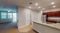 This single-floor residence offers a thoughtfully designed layout with a cohesive blend of modern finishes and functional living spaces. The kitchen serves as a central highlight, showcasing rich cherry wood cabinetry, granite countertops, a peninsula with an undermount sink, and a full suite of stainless steel appliances including a refrigerator, electric range, and microwave. Recessed lighting throughout the kitchen provides a bright and welcoming atmosphere. Light wood-look tile flooring runs through the kitchen and entry areas, transitioning to plush carpet in the living and bedroom spaces. The living area is generously proportioned, featuring a ceiling fan, vertical blinds, and access to a private balcony that brings in natural light. The bedroom is well-sized, also appointed with a ceiling fan, carpeted flooring, and large windows with vertical blinds that allow for ample daylight. An in-unit laundry area is conveniently tucked behind louvered closet doors near the kitchen. The bathroom is cleanly finished with a granite-topped cherry vanity, a full soaking tub with subway tile surround, and wood-look tile flooring. Throughout the unit, neutral wall tones and white trim create a fresh, clean aesthetic that complements the overall design.