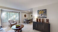 This efficiently designed 1-bedroom, 1-bathroom residence offers a thoughtful floor plan that maximizes every square foot across a single level. The open-concept living and dining area is anchored by soft, neutral-toned carpet and crisp white ceilings, creating a bright and welcoming ambiance. Large windows with slatted blinds allow natural light to fill the living room, which comfortably accommodates a full seating arrangement. A full-wall mirror accent in the dining area visually expands the space, making it feel more open and airy.

The galley-style kitchen is efficiently outfitted with warm wood cabinetry, granite-style countertops, and black appliances including a refrigerator, range, and built-in microwave, all complemented by tile flooring for easy maintenance.

The bedroom is a calm retreat with plush carpeting, a walk-in closet, and a window with outdoor views that bring in natural light. The full bathroom features a tub-shower combination with tile surround, a wood-cabinet vanity with a single sink, and tile flooring, offering a clean and functional design.

Overall, the space presents a cohesive, comfortable layout suited for everyday living, with neutral finishes throughout that provide a versatile and move-in-ready environment.