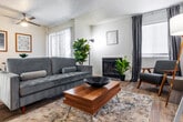 This single-floor residence offers a thoughtfully laid-out living space with a comfortable and modern aesthetic throughout. The living room serves as the heart of the home, featuring a fireplace flanked by indoor greenery, wood-look flooring, and a textured ceiling. Natural light fills the room through multiple windows dressed with blinds and dark curtains, while a sliding glass door opens to an outdoor area, enhancing the sense of openness. A ceiling fan adds comfort, and the dining area sits conveniently adjacent to the living space.

The kitchen is efficiently designed with crisp white cabinetry, dark countertops, and a full suite of black appliances including an electric range, over-the-range microwave, and dishwasher — all set over light wood-look flooring for a clean, contemporary look.

Two bedrooms provide restful retreats, each with plush carpeting, textured ceilings, and windows with blinds for light control. The primary bedroom includes access to a walk-in closet and a bathroom equipped with a vanity featuring dark countertops and a separate shower with a curtain enclosure.

A dedicated laundry area with a full-size washer and dryer rounds out the functional offerings of this well-equipped home.