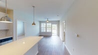 This well-appointed single-floor residence at 1095 Manhattan Blvd in Dayton, Kentucky offers a thoughtfully designed open-concept layout with modern finishes throughout. The kitchen is a standout feature, boasting crisp white cabinetry, stainless steel appliances including a refrigerator, range, microwave, and dishwasher, complemented by a classic subway tile backsplash and quartz countertops. A generous island with pendant lighting adds both functionality and style, while wood-look flooring ties the kitchen seamlessly into the adjoining living and dining area. The living space is bathed in natural light from large windows and a sliding glass door that opens to a private balcony, with a ceiling fan adding to the comfort of the room. The bedrooms are carpeted for warmth and comfort, each featuring windows that frame scenic views of the nearby waterway and surrounding greenery. Two full bathrooms serve the residence — one featuring a tiled walk-in shower with a large vanity mirror, and the other offering a tiled soaking tub and shower combination, both with white cabinetry and wood-look flooring. A dedicated laundry area houses a full-sized washer and dryer with overhead shelving for added storage convenience.