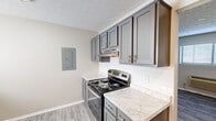 This studio unit in Lexington, KY offers a well-designed, single-floor layout that makes efficient use of its space. The open living area features durable wood-look vinyl plank flooring in a neutral gray tone, soft gray walls, and a textured ceiling that carries throughout the unit. Two windows along the exterior wall allow natural light to fill the room, while a wall-mounted HVAC unit provides climate control.

The kitchen is a standout feature, showcasing gray shaker-style cabinetry with brushed nickel hardware, marble-look countertops, and a classic white subway tile backsplash. Stainless steel appliances — including an electric range and dishwasher — complete the functional cooking space. An electrical panel is conveniently integrated into the kitchen wall.

The bedroom area is open and versatile, continuing the same flooring and neutral color palette, with ample wall space to accommodate various furniture arrangements.

The full bathroom is clean and practical, featuring a white tub and shower combo with tiled surround, chrome fixtures, a toilet, and a vanity with a framed mirror. The consistent use of neutral tones and updated finishes throughout the unit creates a cohesive, move-in-ready environment well suited for comfortable everyday living.