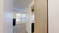 Located in El Paso, TX, this efficient single-floor residence offers 1 bedroom and 2 bathrooms within a well-organized layout. The living room serves as the centerpiece of the home, featuring a striking black-tiled fireplace flanked by multiple windows that fill the space with natural light. A ceiling fan with light fixture adds both comfort and function, while plush carpeting underfoot creates a warm, inviting atmosphere. The textured ceiling carries throughout the common areas.

The kitchen is designed for practicality, featuring warm wood cabinetry, black appliances including a range and refrigerator, and a granite-style countertop with a peninsula breakfast bar that opens to the dining area. A dedicated laundry area with a stacked washer and dryer unit is conveniently accessible just off the kitchen.

The bedroom is a comfortable retreat with carpet flooring, a window allowing natural light, and a closet offering organized storage. Two closets are present throughout the unit for ample storage needs.

Both bathrooms are functional and clean; one features wood-look tile flooring, a full bathtub with white subway tile surround, and standard fixtures. Hallways connect each area of the home efficiently, completing this well-appointed single-level residence.