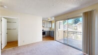 Located at 90 Lund Ave in Hayward, CA, this one-bedroom, one-bathroom unit offers a practical and efficient single-floor layout. The living area features soft carpeting and a textured ceiling, with a sliding glass door that opens to a private balcony overlooking a landscaped outdoor setting, allowing natural light to fill the space. Adjacent to the living area, the compact kitchen is well-appointed with gray cabinetry, granite-style countertops, a stainless steel range with overhead ventilation, and a sink with a window view. The bedroom is a comfortable size, carpeted, and features a large window that brings in natural light and tree-lined outdoor views. A baseboard heater provides climate control in the bedroom. The bedroom is complemented by a walk-in closet with wrap-around shelving and hanging rods, offering practical storage solutions. The bathroom includes a gray vanity with a white countertop, a large mirror, and wood-look flooring, maintaining a clean and cohesive aesthetic throughout. Overall, this unit presents a straightforward, functional design suited for efficient everyday living in the Hayward area.