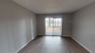 This single-floor residence offers a clean, modern aesthetic with thoughtfully updated finishes throughout. The open living area is highlighted by durable hardwood-style flooring, neutral gray walls, and a sliding glass door fitted with vertical blinds that opens to an outdoor patio, allowing natural light and outdoor views to flow into the space. The textured ceilings add a classic touch consistent throughout the unit.

The kitchen is a standout feature, equipped with warm-toned wood cabinetry, gleaming quartz-style countertops, a stylish mosaic tile backsplash, and black appliances including a refrigerator and range, offering both functionality and contemporary style.

The bedrooms provide a comfortable retreat, featuring plush carpeting, neutral painted walls, and ample natural light. One room features a chair-rail detail and light hardwood-style flooring, adding a refined touch. A dedicated hallway area with hardwood-style flooring and closet access connects the private spaces.

The residence includes two full bathrooms, each featuring a tub-shower combination with a curved curtain rod, a toilet, and hardwood-style flooring. One bathroom additionally features a vanity with a light countertop and mirror. Clean white fixtures and gray walls give both bathrooms a fresh, functional appearance throughout.