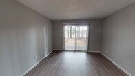This single-floor residence offers a clean, modern aesthetic with thoughtfully updated finishes throughout. The open living area is highlighted by durable hardwood-style flooring, neutral gray walls, and a sliding glass door fitted with vertical blinds that opens to an outdoor patio, allowing natural light and outdoor views to flow into the space. The textured ceilings add a classic touch consistent throughout the unit.

The kitchen is a standout feature, equipped with warm-toned wood cabinetry, gleaming quartz-style countertops, a stylish mosaic tile backsplash, and black appliances including a refrigerator and range, offering both functionality and contemporary style.

The bedrooms provide a comfortable retreat, featuring plush carpeting, neutral painted walls, and ample natural light. One room features a chair-rail detail and light hardwood-style flooring, adding a refined touch. A dedicated hallway area with hardwood-style flooring and closet access connects the private spaces.

The residence includes two full bathrooms, each featuring a tub-shower combination with a curved curtain rod, a toilet, and hardwood-style flooring. One bathroom additionally features a vanity with a light countertop and mirror. Clean white fixtures and gray walls give both bathrooms a fresh, functional appearance throughout.
