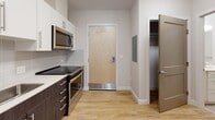 Located at 13 Shetland St in Boston's vibrant Roxbury neighborhood, this single-floor unit offers a thoughtfully designed layout with modern finishes and functional living spaces. The kitchen is a standout feature, outfitted with two-tone cabinetry — crisp white upper cabinets paired with dark lower cabinets — complemented by a light stone countertop, a subway tile backsplash, stainless steel appliances including a refrigerator, range, microwave, and dishwasher, and light hardwood flooring that flows throughout the unit. The entry area provides convenient access to both the kitchen and a well-sized walk-in closet, complete with wire shelving and an electrical panel. The bedroom is bright and airy, featuring a window allowing natural light, built-in open shelving, recessed lighting, and ample space for furnishings. The hallway connects the living areas seamlessly, with clean neutral-toned walls and recessed overhead lighting. The bathroom is outfitted with accessibility-forward features, including grab bars, a tiled floor in a stone-like finish, a vanity with cabinet storage and a stone countertop, and a walk-in shower/tub combination. Throughout the unit, the light hardwood flooring, neutral warm-gray walls, and recessed lighting contribute to a clean, contemporary aesthetic.