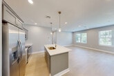 This well-appointed one-bedroom, one-bathroom unit at 12 Station Street in Middleborough, Massachusetts offers a thoughtfully designed layout with modern finishes throughout. The open-concept kitchen and living area serves as the heart of the home, anchored by a striking blue kitchen island with a white quartz countertop and pendant lighting overhead. Gray shaker-style cabinetry, stainless steel appliances, and light hardwood flooring complete the kitchen's contemporary aesthetic. The living area benefits from recessed lighting and sliding glass doors that open onto a private outdoor deck, filling the space with natural light and providing seamless indoor-outdoor access. The bedroom is a comfortable retreat featuring plush carpet, multiple windows with slatted blinds that invite abundant natural light, and recessed ceiling lighting. A dedicated closet provides practical storage. The full bathroom is finished with large-format neutral tile surrounding a soaking tub and shower combination, complemented by tile flooring and a window for natural light. Neutral, soft-toned walls throughout the unit create a clean, cohesive ambiance that is both calm and move-in ready. The unit also includes a separate room with hardwood flooring, suitable for use as a home office or flex space.