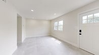 Located at 2800 US 6 in Blakely, PA, this two-story, 3-bedroom, 2-bathroom home offers a clean, modern aesthetic throughout both floors. The main level is finished with large-format light gray tile flooring that runs seamlessly through the living room, kitchen, and bathrooms, creating a bright and cohesive feel. Recessed lighting illuminates the open living area, which features neutral walls, crisp white trim, and natural light from multiple windows and a sliding glass door. The kitchen is well-equipped with dark shaker-style cabinetry accented by matte black hardware, white quartz countertops, a classic subway tile backsplash, stainless steel appliances including a dishwasher and range, and a single-basin sink with a matte black faucet. The main level also includes a utility room and laundry area. Upstairs, three bedrooms feature warm light wood-style flooring, ample natural light, and clean white walls. The spacious primary bedroom includes two double-door closets with black hardware. Additional bedrooms provide comfortable, flexible living space. Two full bathrooms serve the home, finished consistently with the home's modern, minimalist palette. A hallway and two staircases connect the floors efficiently, completing this thoughtfully updated residence.