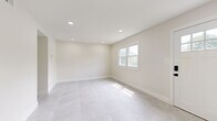 Located at 2800 US 6 in Blakely, PA, this two-story, 3-bedroom, 2-bathroom home offers a clean, modern aesthetic throughout both floors. The main level is finished with large-format light gray tile flooring that runs seamlessly through the living room, kitchen, and bathrooms, creating a bright and cohesive feel. Recessed lighting illuminates the open living area, which features neutral walls, crisp white trim, and natural light from multiple windows and a sliding glass door. The kitchen is well-equipped with dark shaker-style cabinetry accented by matte black hardware, white quartz countertops, a classic subway tile backsplash, stainless steel appliances including a dishwasher and range, and a single-basin sink with a matte black faucet. The main level also includes a utility room and laundry area. Upstairs, three bedrooms feature warm light wood-style flooring, ample natural light, and clean white walls. The spacious primary bedroom includes two double-door closets with black hardware. Additional bedrooms provide comfortable, flexible living space. Two full bathrooms serve the home, finished consistently with the home's modern, minimalist palette. A hallway and two staircases connect the floors efficiently, completing this thoughtfully updated residence.