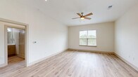 Located in Ocean Isle Beach, NC, this well-designed single-story home offers 2 bedrooms and 2 bathrooms across a thoughtfully laid-out floor plan. The open-concept living, dining, and kitchen area serves as the heart of the home, featuring light hardwood-style flooring that flows seamlessly throughout. The modern kitchen is equipped with stainless steel appliances, a central island with a white quartz countertop and undermount sink, shaker-style cabinetry with gold hardware, a subway tile backsplash, and stylish pendant lighting — a functional and visually appealing space for cooking and entertaining. The spacious primary bedroom includes a ceiling fan, natural light from a window with outdoor views, and access to a well-appointed en-suite bathroom featuring a wide vanity with white quartz countertops, gold hardware accents, and a large mirror. The second bedroom is bright and versatile, also benefiting from natural light. Three closets, including a walk-in with wire shelving, provide ample storage. A dedicated laundry area houses a full-size washer and dryer with overhead shelving. The attached garage offers additional storage and parking. Throughout, the home maintains a clean, neutral palette with crisp white walls and light flooring, creating a bright and welcoming ambiance.