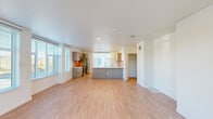 Located at 9950 NE Gibbs Dr in Hillsboro, Oregon, this three-story townhome offers three bedrooms, three bathrooms, and a well-designed layout spread across multiple levels. The ground floor features a private attached garage with an automatic opener and direct interior access through a dedicated entrance hallway finished with light hardwood-style flooring. The main living level is anchored by a bright, open-concept kitchen and living area flooded with natural light from large windows fitted with blinds. The kitchen features warm wood-tone cabinetry, a tile backsplash, stainless steel appliances, a central island with a sink, and generous counter space — ideal for both cooking and entertaining. A bonus room on this level offers additional flexible living space, complete with built-in cabinetry, a tile backsplash, and a large window. The upper floor houses all three bedrooms, including a spacious primary suite, alongside three full bathrooms. Each bathroom is finished with light wood-tone vanities, white quartz countertops, backlit mirrors, and tub-shower combinations with clean white tile surrounds. Six closets throughout the home, including walk-in storage with built-in shelving, provide ample organization. Carpeted staircases with warm wood handrails connect all three levels, and a laundry area adds everyday convenience.
