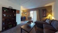 This single-story home located at 8714 Redwood Ct in Tampa, Florida offers a practical and comfortable layout across several well-defined living spaces. The living room serves as the central gathering area, featuring carpet flooring, textured ceilings, and a sliding glass door that allows natural light to filter in. An accent wall adds a touch of contrast to the space, which flows seamlessly into an adjacent dining area illuminated by a chandelier overhead.

The kitchen is efficiently arranged in a galley-style configuration, equipped with cream cabinetry, laminate countertops, a double sink, and white appliances including a range and full-size refrigerator. Tile-style flooring runs throughout the kitchen, providing a durable and easy-to-maintain surface.

The bedrooms are carpeted and offer a cozy atmosphere, each featuring closets with louvered bifold doors and windows that bring in natural light. The rooms provide adequate space for standard bedroom furnishings.

The bathroom includes a full tub-shower combination, a toilet, and a vanity with a single sink and storage below, all finished in neutral tones that contribute to a clean and functional aesthetic throughout the home.