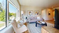 Located in the serene Linley Valley neighbourhood of Nanaimo, BC, this well-appointed 3-bedroom, 2-bathroom unit offers a thoughtfully designed single-level layout with a warm, contemporary aesthetic throughout. Light wood-tone flooring flows seamlessly across the open-plan living and kitchen area, creating a cohesive and inviting atmosphere.

The modern kitchen is a standout feature, showcasing flat-panel cabinetry in crisp white and soft taupe tones, black hardware accents, white quartz countertops, and stainless steel appliances. A peninsula with seating for two serves as both a functional workspace and a casual dining spot.

The living room is bright and welcoming, benefiting from large windows that frame lush, verdant views of the surrounding trees — filling the space with abundant natural light. The open layout connects the living and kitchen areas comfortably.

Three bedrooms offer restful retreats with neutral wall tones and soft natural light. The primary bedroom is a well-proportioned space and includes a dedicated walk-in closet with built-in shelving. The two bathrooms are finished cleanly in white, with one featuring a soaker tub/shower combo and the other a walk-in shower with curtain enclosure and marble-look tile flooring.