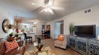 Located at 1601 Hogan Ln in Conway, Arkansas, this single-story residence offers a functional and comfortable layout across two bedrooms and two full bathrooms. The open-concept living and dining area flows seamlessly into the kitchen, creating a connected, sociable atmosphere. Ceiling fans are present throughout the home, contributing to both comfort and air circulation. The living room features plush carpeting, a textured ceiling, and ample space for relaxed seating arrangements. The kitchen is well-equipped with light wood cabinetry, a peninsula breakfast bar, full appliance suite including a refrigerator, range, microwave, and dishwasher, plus durable hardwood-style flooring. A dedicated dining area sits adjacent to the kitchen, ideal for everyday meals. The primary bedroom is generously proportioned, offering a large window with outdoor views, soft carpet, a ceiling fan, and dual closets providing excellent storage. A connected bathroom adds convenience. The second bedroom similarly features carpet, a ceiling fan, and closet access, with its own adjacent bathroom. Both bathrooms include a tub-shower combination with sliding glass doors, light wood vanities, and overhead cabinetry. A hallway connects the private and shared spaces efficiently, and an in-unit laundry closet adds everyday practicality.