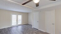 This two-story home in North Augusta, South Carolina offers a practical and comfortable layout spread across two floors. The main level features hardwood-style flooring throughout the living areas, highlighted by a tray ceiling with a ceiling fan and French doors that invite natural light and provide outdoor access. A hallway lined with louvered closet doors leads through the main floor, connecting the living spaces seamlessly. The galley-style kitchen is well-appointed with gray shaker cabinets, white subway tile backsplash, light countertops, and white appliances including a range and refrigerator, all complemented by light-toned vinyl plank flooring and a window for natural light. The upper level houses the bedrooms, including a generously sized primary bedroom with dual closets, carpet flooring, and a ceiling fan. The additional bedrooms are similarly carpeted and feature ceiling fans, closets, and windows with outdoor views. The full bathroom is clean and functional, offering a tub/shower combination, a vanity with marble-style countertop, and wood-look tile flooring. Throughout the home, neutral tones, textured ceilings, and consistent finishes create a cohesive and move-in-ready atmosphere.