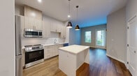 This thoughtfully designed 2-bedroom, 1-bathroom residence at 22 Mount Carmel Way in Worcester, MA offers a modern, open-concept layout with clean lines and contemporary finishes throughout. The kitchen serves as the heart of the home, featuring light wood cabinetry, white quartz countertops, a full suite of stainless steel appliances including a refrigerator, range, microwave, and dishwasher, a subway tile backsplash, and a central island with pendant lighting overhead. The kitchen flows seamlessly into the living area, which is brightened by natural light from large windows and finished with warm hardwood-style flooring. The two bedrooms are well-proportioned, with the primary bedroom offering a comfortable footprint, hardwood-style floors, and a window for natural light. A dedicated closet provides additional storage. The bathroom is clean and modern, featuring a glass-enclosed walk-in shower with gray subway tile, wood-look flooring, and a vanity with ample counter space. Neutral gray walls and consistent flooring create a cohesive aesthetic throughout the single-floor layout, offering a bright, move-in-ready living environment in Worcester's Mount Carmel neighborhood.