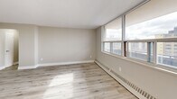 Located at 1251 King St W in Toronto's vibrant King West neighbourhood, this well-appointed one-bedroom, one-bathroom unit offers a thoughtfully designed layout across a single floor. Light-toned hardwood flooring runs throughout the living areas and bedroom, lending a clean, cohesive aesthetic to the space.

The combined kitchen and living room forms the heart of the unit. The kitchen is outfitted with white shaker-style cabinetry extending to the ceiling for generous storage, white subway tile backsplash, white quartz countertops, and a full suite of stainless steel appliances including a refrigerator, stove, and dishwasher. A peninsula with built-in drawers provides additional prep space and storage. Large floor-to-ceiling windows and a balcony access door flood the living area with natural light and offer open city views.

The bedroom is a well-proportioned retreat featuring a window with city views, a built-in closet with panel doors, and baseboard heating. Warm neutral wall tones and light hardwood flooring complete the room.

The bathroom is finished with large-format grey tile flooring and tub surround, a white vanity with gold hardware, and a combined tub and shower. A hallway connects all rooms, completing this clean, modern unit.